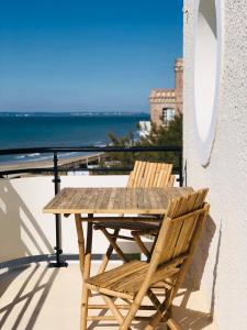 a wooden table and chair on a balcony with the ocean at Le Paquebot in Villerville