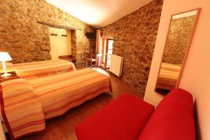 um quarto de hotel com duas camas e um sofá vermelho em Hostellerie du Vieux Moulin em Duilhac