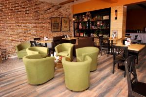 um restaurante com cadeiras e mesas verdes e uma parede de tijolos em Madanur Hotel em Karakol