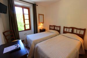 a room with two beds and a table and a window at Hostellerie du Vieux Moulin in Duilhac