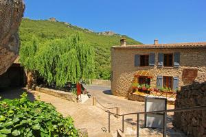 une maison en pierre avec un arbre en face de celle-ci dans l'établissement Hostellerie du Vieux Moulin, à Duilhac-sous-Peyrepertuse