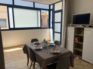 uma sala de jantar com uma mesa e cadeiras e uma televisão em MareinSicilia: Appartamenti del Melo em Marina di Ragusa