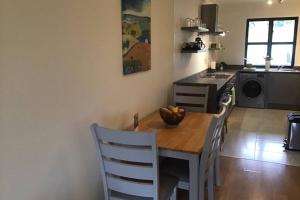 een keuken met een houten tafel en witte stoelen bij Waterfront apartment completely refurbished in Westport