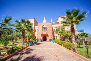 a building with palm trees in front of it at Kasbah Ait Oumghar in Demnat