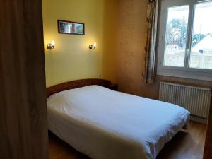 a bedroom with a white bed and a window at Home des Pins SARL in Saint-Pierre-Quiberon