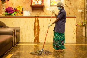 une femme en masque nettoyant le sol à l'aide d'un cyclomoteur dans l'établissement Hotel Ragavendra Rameswaram, à Rameswaram