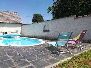 two chairs and a swimming pool in a yard at gîte coeur de champagne in Romery