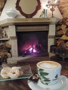 a cup of coffee and a plate of donuts in front of a fireplace at Eco Hotel Nos in Silleda