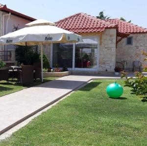 a house with an umbrella and a lawn with a green ball at Kellys House in Nea Plagia