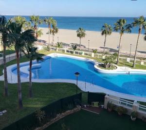 ein großer Pool neben einem Strand mit Palmen in der Unterkunft Primera Linea De Playa in Roquetas de Mar