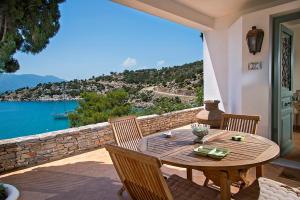 una mesa de madera y sillas en un patio con vistas al agua en Unique Villa on the Island of Poros en Poros