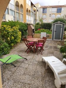 un patio con tavolo, sedie e un edificio di Appartement T2 avec son rez de jardin de 40 m2 5 couchages 250m de la plage et 15km de l'Arena a Narbonne-Plage