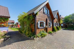 une maison en bois avec du lierre sur son côté dans l'établissement Domki Rekin Podgrzewany basen z brodzikiem oraz klimatyzacją, à Rewal