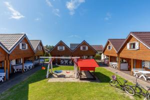 un parque infantil en una localidad con casas de madera en Domki Rekin en Rewal