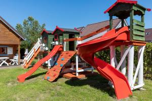 - une aire de jeux avec toboggan dans la pelouse dans l'établissement Domki Rekin Podgrzewany basen z brodzikiem oraz klimatyzacją, à Rewal