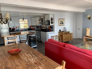 a living room with a red couch and a kitchen at Chalet chez les Petit in Grandes-Bergeronnes