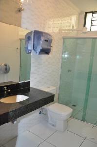 a bathroom with a shower and a toilet and a sink at Hotel Graunas in São Carlos