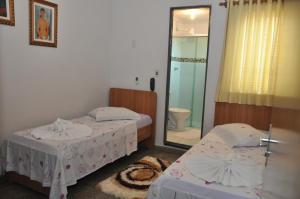 two beds in a room with a mirror and a bathroom at Hotel Graunas in São Carlos