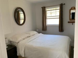 a bedroom with a white bed and a mirror at Chalet chez les Petit in Grandes-Bergeronnes