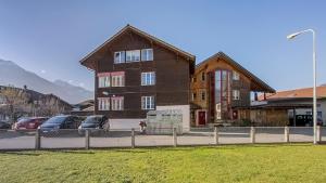 een groot houten gebouw met auto's geparkeerd op een parkeerplaats bij Hasel in Interlaken