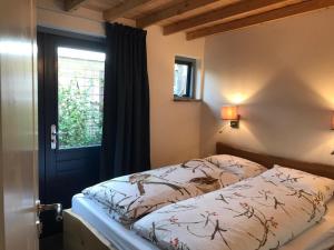 a bedroom with a bed and a window at Heerlijk huisje vlakbij de duinen van Oostvoorne in Oostvoorne