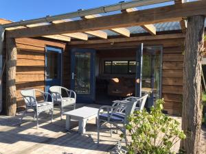a patio with chairs and a table and a wooden house at Heerlijk huisje vlakbij de duinen van Oostvoorne in Oostvoorne