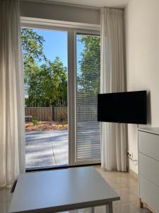 a living room with a tv and a large window at Charivy’s Guesthouse in Koudekerke