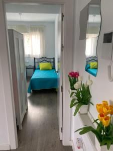 a bedroom with a bed and a mirror and flowers at Ático de lujo 90m de terraza y jacuzzi privado en Cabria, Almuñecar in Almuñécar