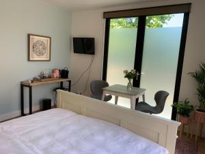 a bedroom with a bed and a table and a window at Charming private guesthouse Air by the Beach in Zandvoort