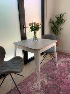 a white table with a vase of flowers on it at Charming private guesthouse Air by the Beach in Zandvoort