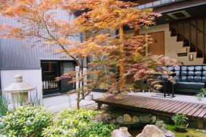 uma árvore de bordo em frente a um edifício com um banco em Guesthouse Soi em Quioto