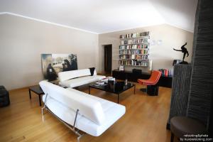 a living room with white furniture and a book shelf at Quarto Piano Rooms in Genoa