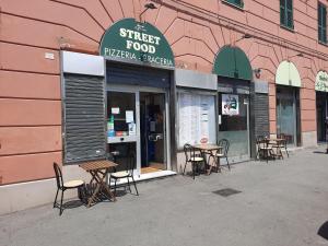 a set of tables and chairs outside of a street food pizzeria at Hotel Le Tre Stazioni in Genoa