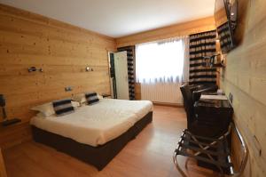 1 dormitorio con 1 cama y 1 silla en una habitación en Hôtel Edelweiss, en Briançon