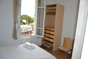 ein Schlafzimmer mit einem Bett, einem Fenster und einem Stuhl in der Unterkunft Les Lauriers in Villefranche-sur-Mer