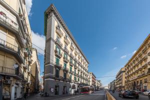un grand bâtiment dans une rue de la ville avec des voitures dans l'établissement 'Na Siesta, à Naples