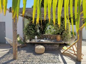 um pátio com um banco e uma árvore em Derrière la plage : suite, patio et pergola em Le Bois-Plage-en-Ré