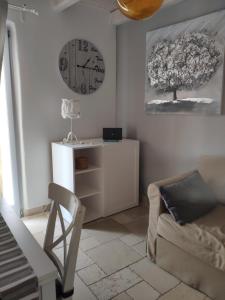 una sala de estar con un reloj en la pared y una silla en Dimora Mediterranea, en Polignano a Mare