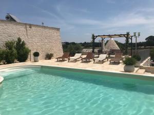a large swimming pool with chairs and a patio at Cappelluzzo in Cisternino