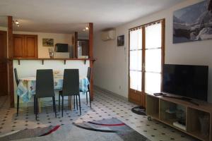 ein Wohnzimmer mit einem Tisch, Stühlen und einem TV in der Unterkunft Le Merle Enchanteur in Paladru