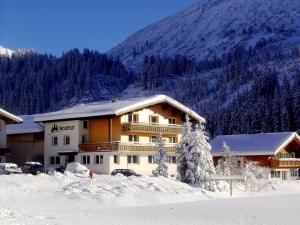 a building in the snow in front of a mountain at Pension Waldhof in Lech am Arlberg