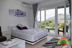 a white bedroom with a bed and a balcony at Apartmani Pantovic - Apartman 2 in Trebinje