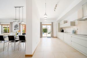 Villa Ofelia 46 by Destination Algarve في Santo Amaro: مطبخ مع دواليب بيضاء وغرفة طعام