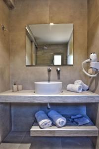 a bathroom with a sink and a mirror and towels at Liogerma Studios in Trapezaki