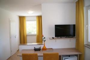 a living room with a television and a table with chairs at Rooms Magdalena Krk in Krk