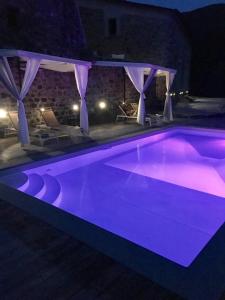 una piscina con iluminación púrpura por la noche en Encanto Di Arlia en Fivizzano