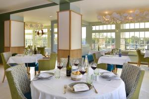 un restaurant avec des tables et des chaises blanches et des verres à vin dans l'établissement Suites du Cabinet Vert, à Orléans