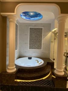 Phước Hưng 1 Hotel في فينه لونج: حوض استحمام في حمام به اعمدة