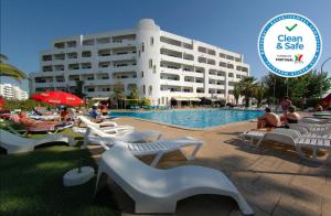 a hotel with a swimming pool with people sitting around it at Apartamentos Turisticos Silchoro in Albufeira