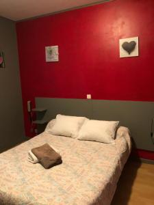 a bedroom with a bed with a red wall at La Trinite in Saint Firmin